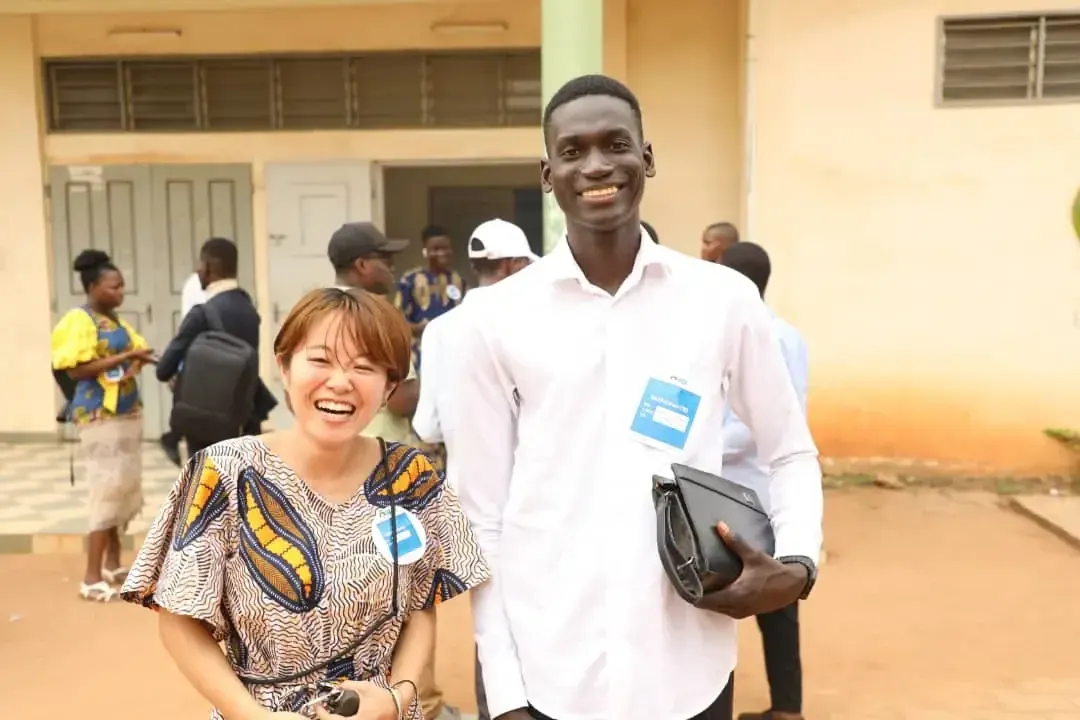 A smiling young woman and young man outside the building.