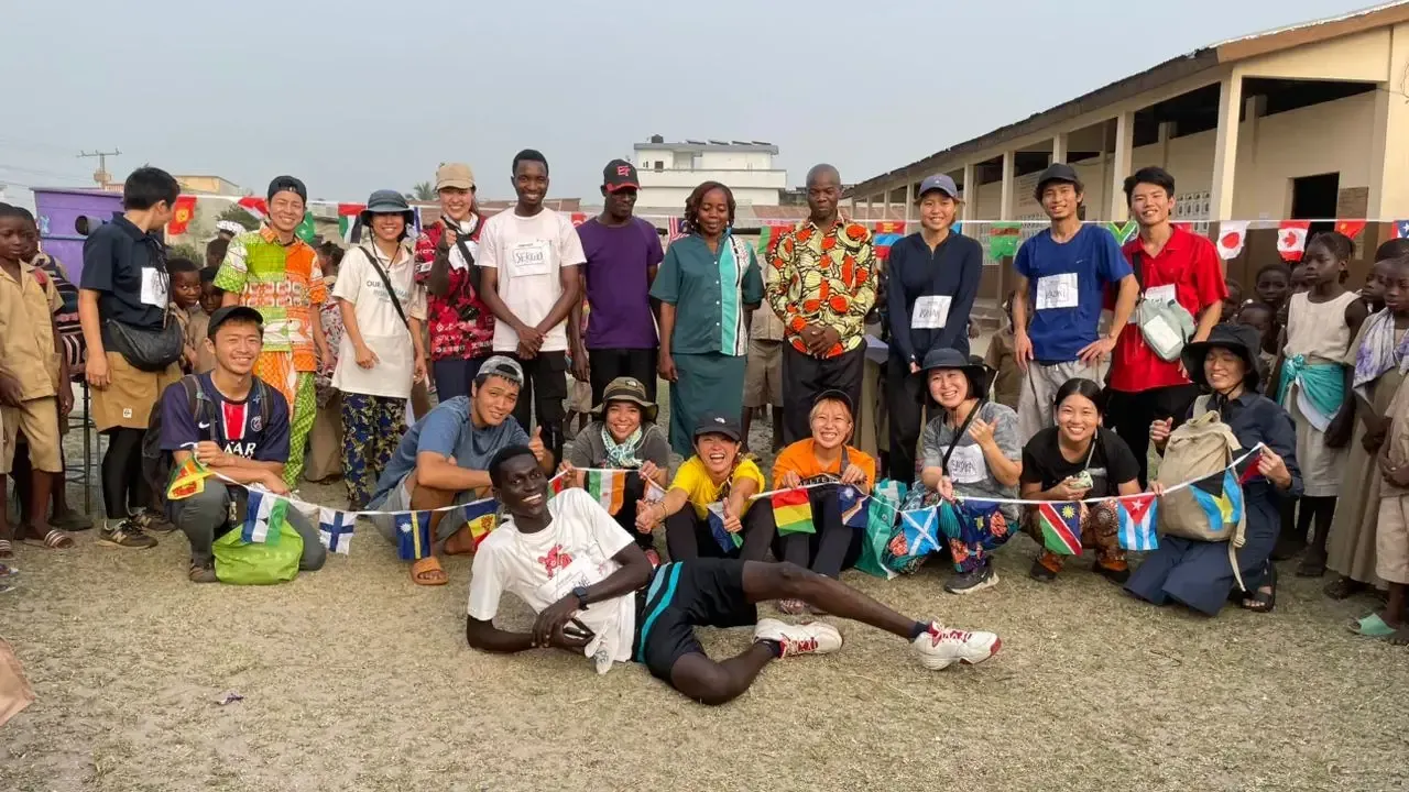 International volunteers and young Beninese people under flag bunting.