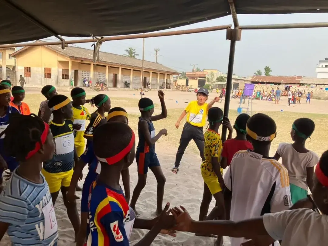 Children take part in a group game under a shelter.
