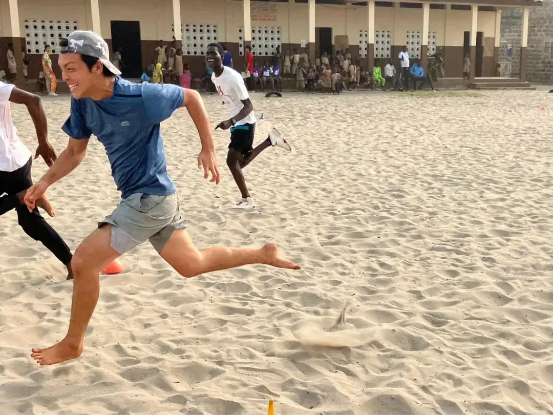 A volunteer runs barefoot during a race on the sand.