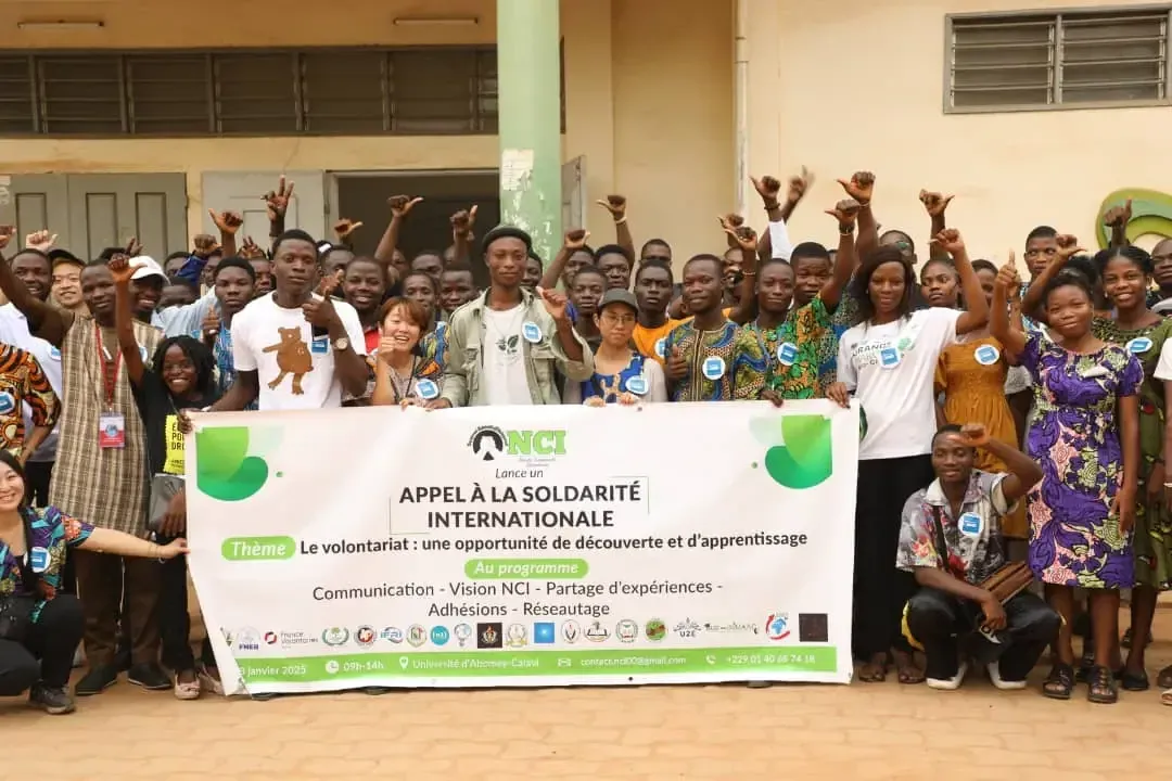 Around a hundred young people with raised arms behind the event banner.
