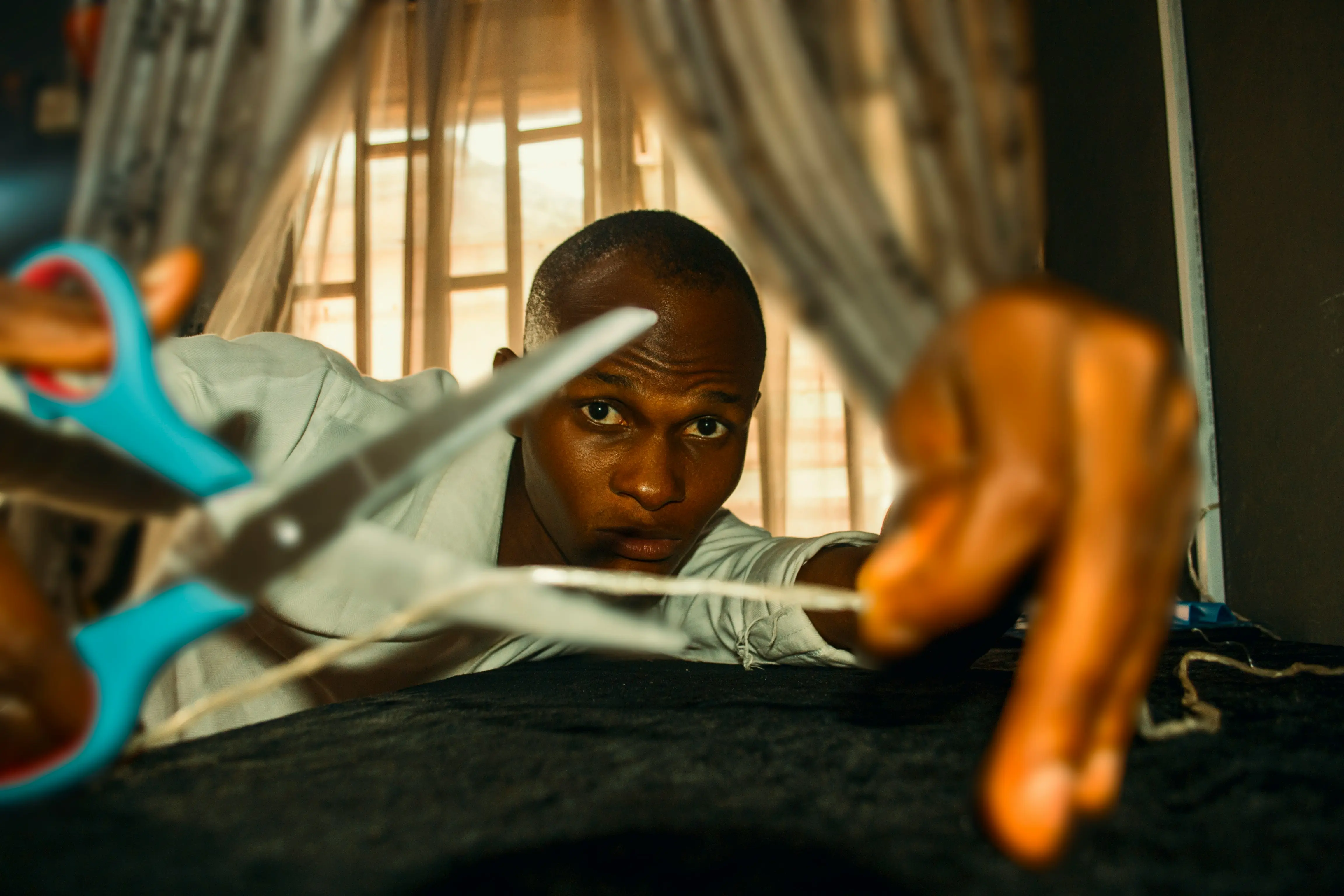 Kenyan artisan sewing a wax fabric patch onto a t-shirt.